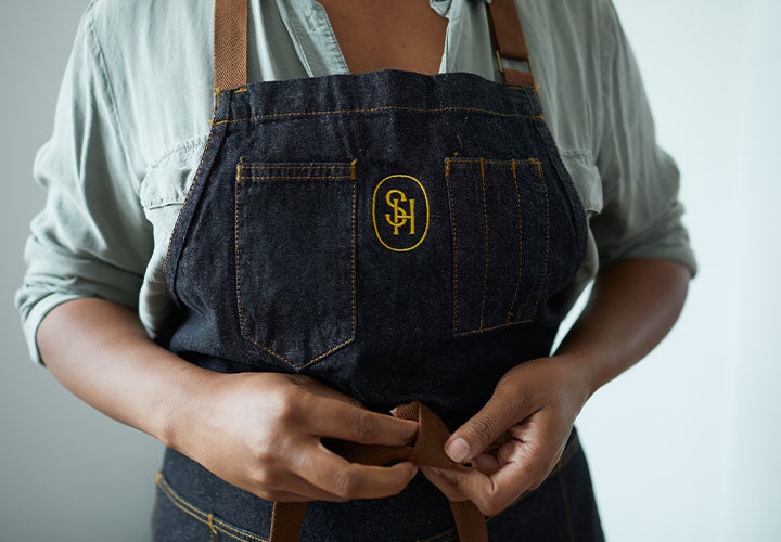 Employee at The Spice House putting on an apron with the Spice House logo.