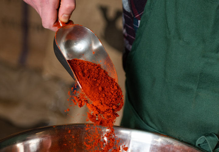 A large spoonful of gorgeous Hungarian sweet Paprika pouring into a bowl.