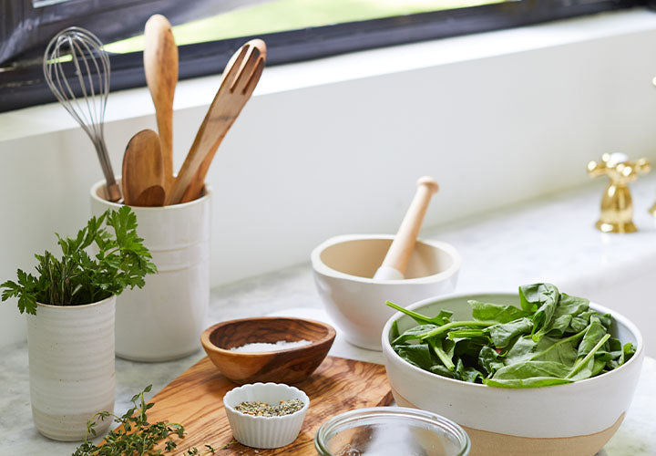 Assembling a delicious green salad with fresh spices in a sunlit kitchen.