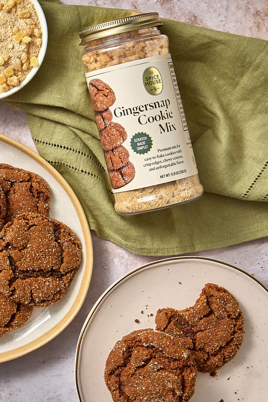 Gingersnap cookies on a platter with a jar of cookie mix and other baked goods.